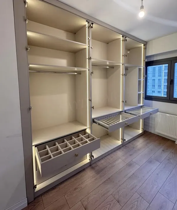 Floor-to-ceiling wardrobe with lit shelves, hanging rails and pull-out drawers
