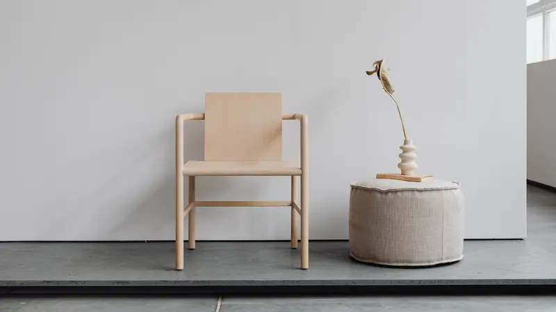 Minimal wooden chair styled with a side table and sculpture